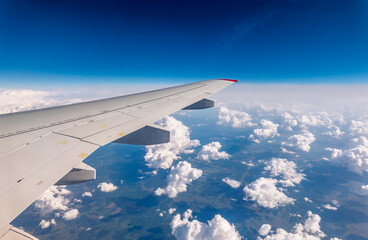 Fototapeta premium View from the airplane window at a beautiful cloudy sky and the airplane wing