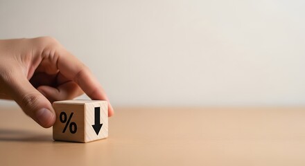 Hand pressing wooden block with percentage symbol and downward arrow indicating decline
