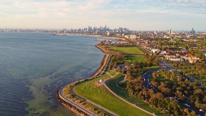 Fototapeta premium Aerial View of Melbourne City Skyline and Port Phillip Bay at Golden Hour with Coastal Parks and Paths