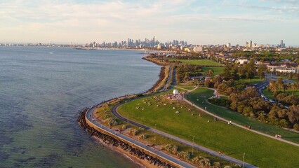 Fototapeta premium Aerial View of Melbourne's Coastal Parkland and Vibrant Skyline Under Golden Hour Light