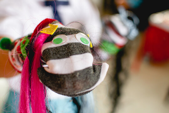 Child holding colorful handmade sock puppet with googly eyes