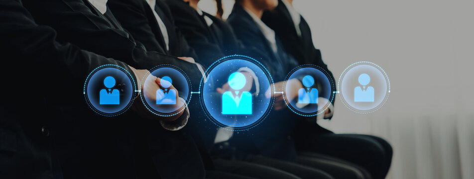 A group of business professionals in formal attire engaged in a session, with digital icons illustrating teamwork and networking in a contemporary office setting. Trope