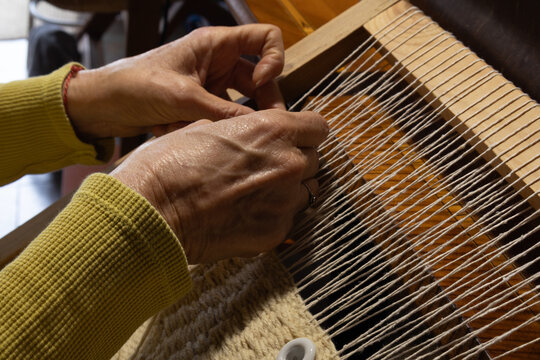 Woman&rsquo;s hands weaving a handmade tapestry on a loom. Concept small business