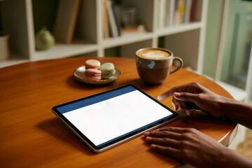 Person using tablet with coffee and macarons