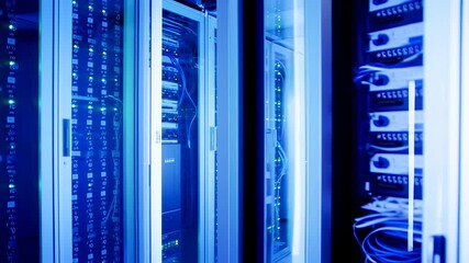 Servers and data cables in a blue-lit server room. Data center infrastructure, networking tech - Powered by Adobe
