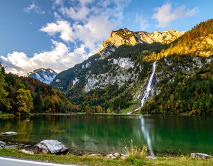 Majestic mountains reflect in tranquil emerald waters under a sunny sky