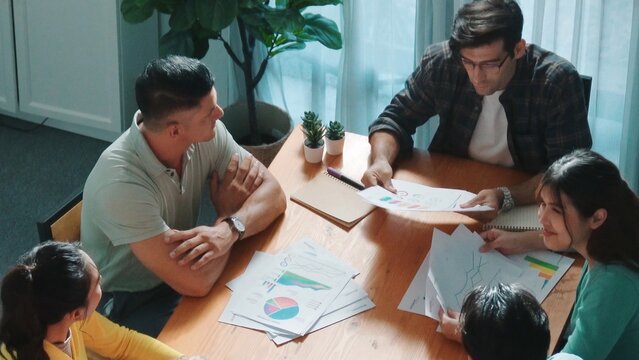 Top down view of start up business team holding paper while discussing about financial idea. Aerial view of smart diverse people brainstorming idea while looking at stock market statistic. Symposium. - Powered by Adobe