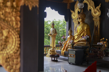Serene golden Buddha statue at peaceful temple shrine. ornate interior with traditional Asian architecture creates spiritual atmosphere for meditation and worship