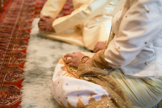 Close up of South Asian couple kneeling during traditional wedding ceremony. bride and groom show serene respect, sitting on floor for sacred Hindu ritual
