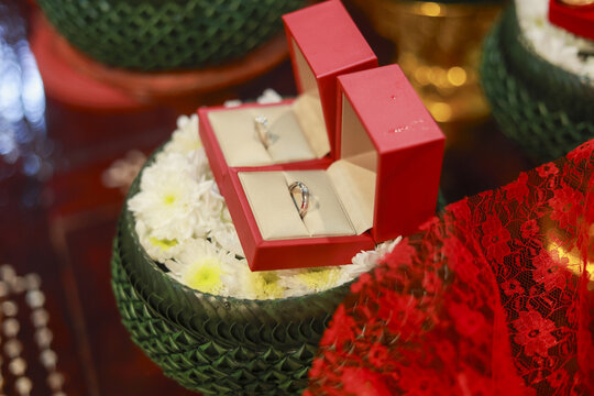Two wedding ring in red box for traditional ceremony. beautiful gold engagement couple ring on white flower tray, symbol of love, commitment, and celebration