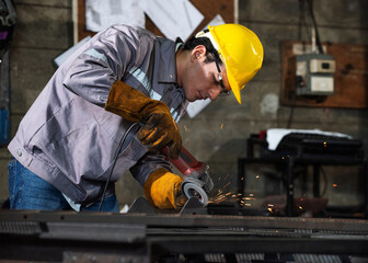 Factory welder shapes metal with grinder as worker focuses precision workshop, sparks fly, safety...