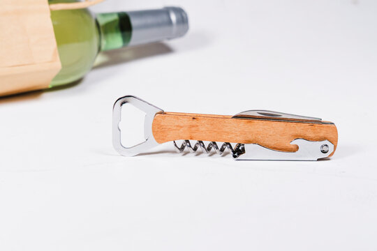 wooden bottle opener, corcscrew with switchblade, bottle of wine in eco craft paper bag on white background, commercial photo concept