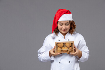 Young chef wearing a santa hat proudly presents a box of delicious homemade christmas cookies