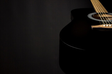 black guitar on a dark background. a shadow. the background. close-up.