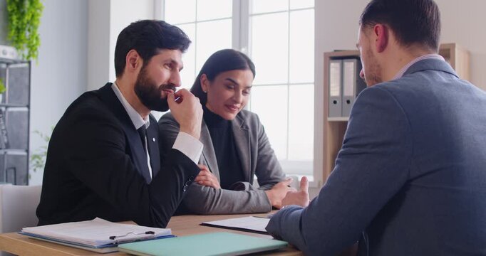 Couple as client discusses contract with financial consultant, banker, or investment agent during office meeting, focusing on planning in a professional environment with careful attention.
