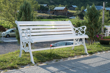 a white, weatherproof garden bench, likely made of PVC or cast ironThis type of bench is designed for outdoor use 