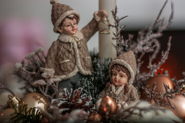  a close-up of Christmas-themed decorative figurines and ornaments. The central figures are two small, intricately detailed figurines of children dressed in winter clothing, 