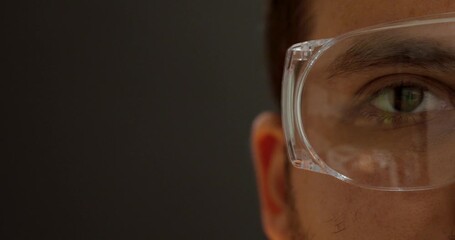 Side close-up of a person wearing transparent safety glasses, symbolizing workplace protection, safety awareness, and precision at work.