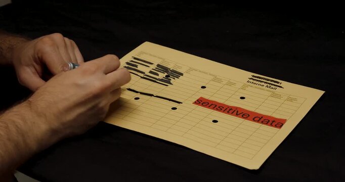 A person uses a black marker to redact confidential information on a document labeled &ldquo;sensitive data,&rdquo; emphasizing privacy protection and data security.