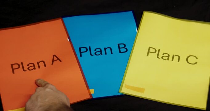 A hand points to three colorful folders labeled Plan A, Plan B, and Plan C, symbolizing the process of decision-making, evaluation, and strategic choice.