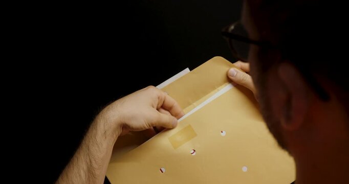 A man opens a brown envelope labeled &ldquo;sensitive data&rdquo; and takes out a document revealing a printed password, illustrating outdated or insecure password delivery methods.