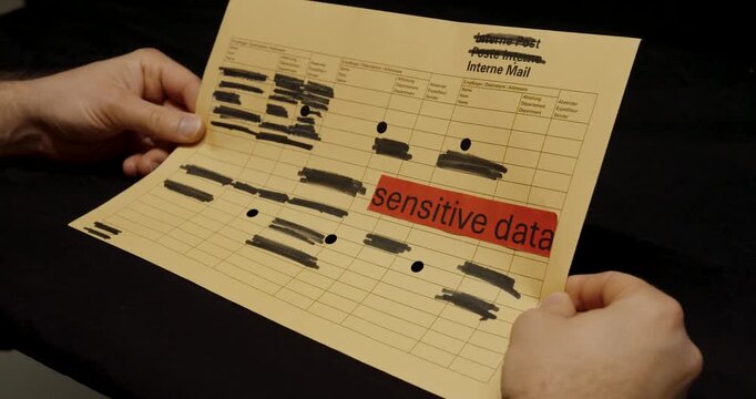 A close-up of a paper document marked &ldquo;sensitive data&rdquo; with multiple sections blacked out, symbolizing secure handling and protection of confidential information.