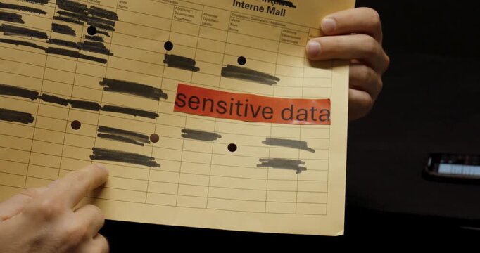 A person points to a document labeled &ldquo;sensitive data,&rdquo; explaining the importance of redacting and protecting confidential information to ensure data security.