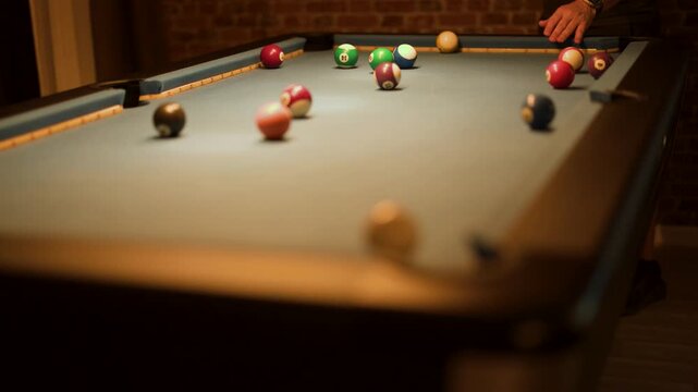 Player Strikes Cue Ball on Indoor Billiard Table in Low Light