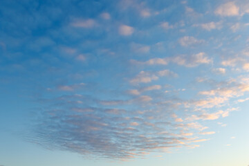 A serene sky scene with gentle pastel clouds illuminated by warm evening light, creating a peaceful and open atmosphere perfect for backgrounds.