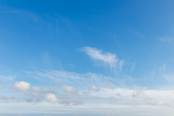 Clear blue sky with delicate cirrus streaks and scattered cumulus clouds. Soft cloud formations add texture to the serene sky, making this image ideal for nature backgrounds or weather themes.