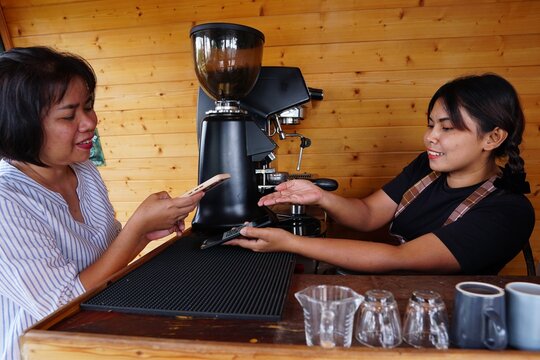 Convenient payment: The customer hands over her mobile phone to the barista to complete the digital transaction at the counter.
