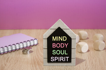 Concept words Mind body soul spirit on a black board. Beautiful purple background. Notebook and silver coins on the table. Lifestyle concept.
