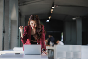 Young businesswoman celebrating success viewing laptop screen