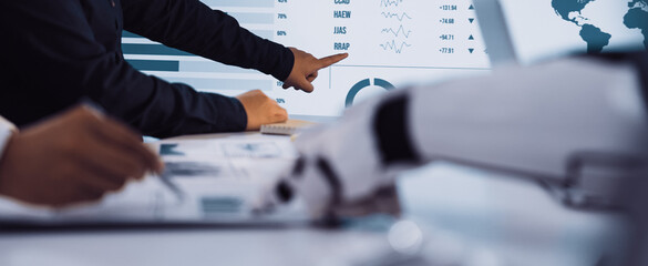 Two business professionals engage in a data analysis session at a modern office. They interact with digital displays while utilizing advanced technology tools.Noogenesis