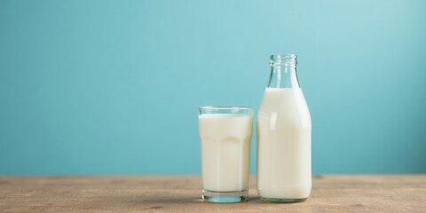 Refreshing Glass and Bottle of Milk on Wooden Table Against Teal Background