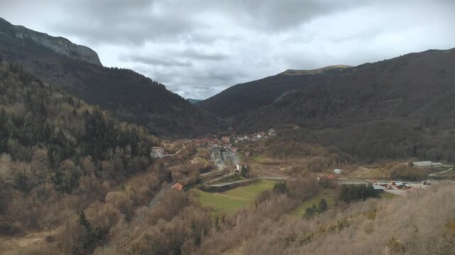 Aerial clip approaching Isaba village going over fields and connecting road on a cloudy, early spring day.