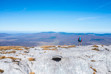 Lone Hiker Standing on Mountain Cliff Overlooking Vast Autumn Valley &ndash; Aerial Style Landscape Shot