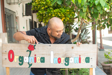 Worker installing handmade organic inorganic sign outdoors