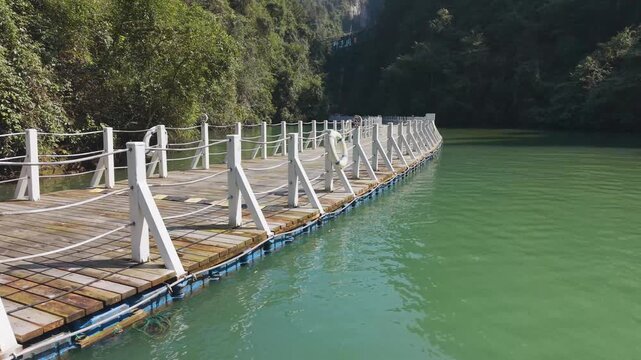 Close fly by aerial of the Shiziguan Floating Bridge in Hubei, showing modular HDPE pontoon floats and wooden deck structure on calm river water.