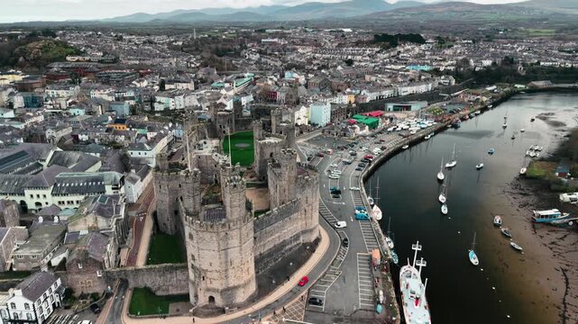 Majestic Caernarfon Castle slow clockwise drone rotate, revealing estuary, North Wales, UK
