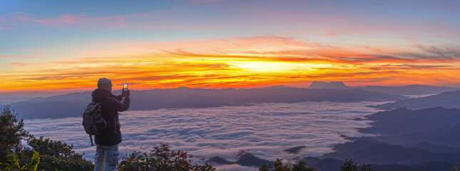 Male Hiker with backpack using smartphone taking photos mountains landscape. Sharing travel...