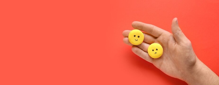 Hand with happy and sad emoticons on red background. Customer experience concept