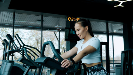 A woman is actively using an elliptical training machine in a gym setting