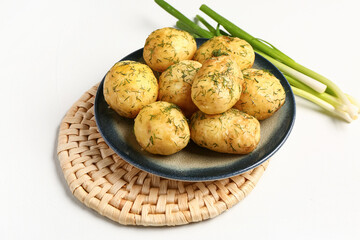 Plate of boiled baby potatoes with dill and green onion on white background