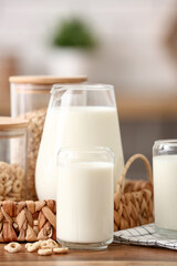 Glasses and jug of fresh milk with cereal rings on wooden table in kitchen