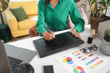 Female web designer drawing with graphic tablet at table in office, closeup