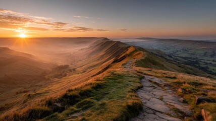 Golden sunrise over mam tor mountain ridge with glowing sky and rolling hills in the peak district, united kingdom creating a peaceful scenic landscape view