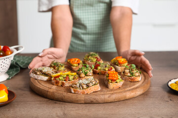 Woman with tasty vegan bruschettas at table in kitchen, closeup