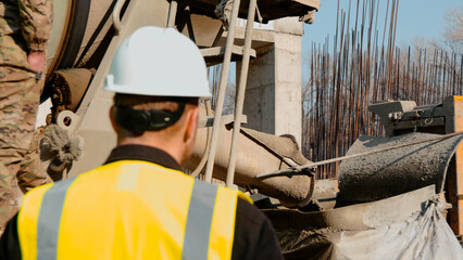A construction worker in a high-visibility vest is working at a building