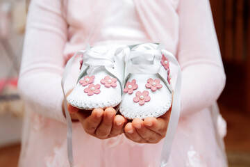 Hands of a little girl holding baby sister`s shoes.